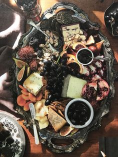 an assortment of cheeses, crackers and fruit on a platter