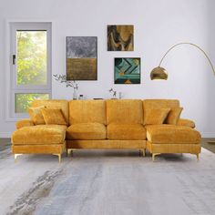 a living room with yellow couches and pictures on the wall above it, along with an area rug