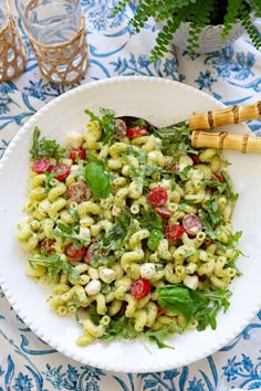 a white bowl filled with pasta salad on top of a blue and white table cloth