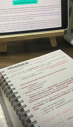 an open notebook sitting on top of a desk next to a computer monitor