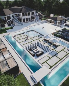 an aerial view of a large house with a pool in the foreground and several lounge chairs around it