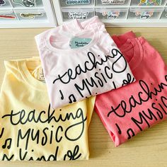 three t - shirts with writing on them are sitting on a table in front of some books