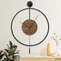 a clock that is on the wall next to a potted plant and some vases