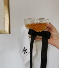 a person holding a glass bowl with liquid in it and a black ribbon around the bottom