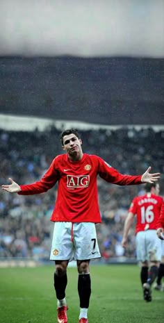 a man standing on top of a soccer field holding his arms out in front of him