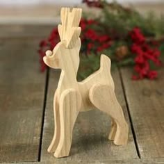 a small wooden toy dog sitting on top of a wooden table next to red flowers