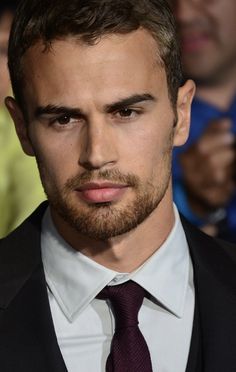 a close up of a person wearing a suit and tie with people in the background