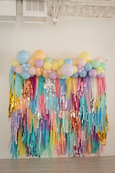 balloons and streamers are hanging from the ceiling in front of a wall that is decorated with sequins