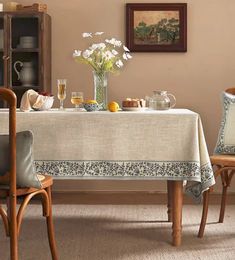 a dining room table with two chairs and a vase filled with flowers