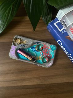 an assortment of items sitting on top of a wooden table next to some books and a plant