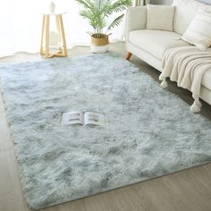 a living room with a white couch and book on the floor in front of it