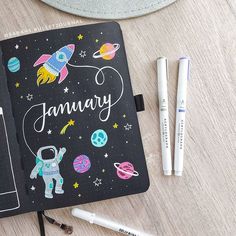 an open notebook with the word january written on it next to some markers and pens