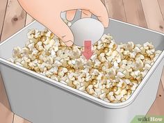 a person scooping popcorn into a tin with a red arrow pointing to the top