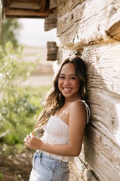 a beautiful young woman leaning against a stone wall