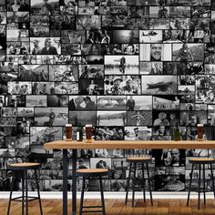 a table with two stools in front of a wall full of black and white photos