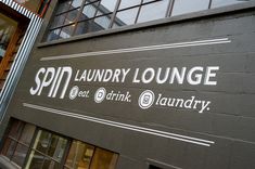 there is a sign on the side of this building that says spin laundry lounge, eat drink laundry