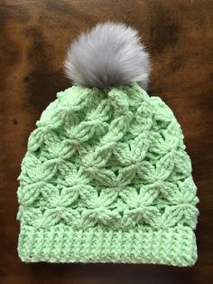 a green knitted hat with a white pom - pom