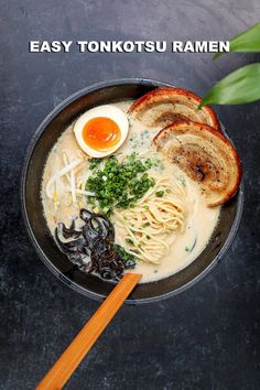 a bowl filled with noodles and vegetables next to chopsticks on a black surface