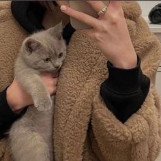 a woman is taking a selfie with her phone while holding a cat in her arms