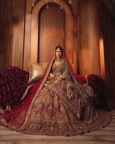 a woman sitting on top of a couch wearing a red and gold wedding dress