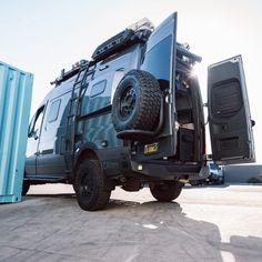 an off - road vehicle is parked in front of a shipping container with its door open