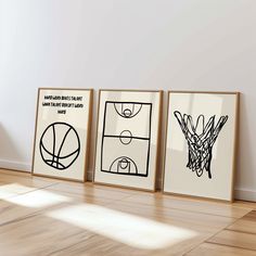 three framed basketball posters on the wall in an empty room with hard wood flooring