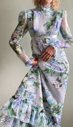 "Incredible vintage 1960s ethereal floral maxi dress with sheer sleeves, empire waist with long blue satin ribbon that forms a bow at the back, high ruffled Victorian collar neckline, tiered ruffled hemline and zipper closure at the back. The floral fabric is just stunning in a baby blue, pink, purple, green and white colour palette. The dress is fully lined (except for sleeves). Would fit a size x-small to small but please see measurements below.  Maker/Designer: Irving Nadler - Montreal Condition: Very good vintage condition  Measurements (taken with garment lying flat, unstretched - double for bust/waist/hip):               shoulders seam to seam: 15\"               bust: 17\"                 empire waist: 14\"               hip: 19\"               length (shoulder to bottom hem): 53.5\ Spring Formal Vintage Maxi Dress, Vintage Floral Print Maxi Dress For Wedding, 1970s Style Silk Dresses For Spring, Dress With Sheer Sleeves, Victorian Collar, Floral Dress Outfits, Blue Pink Purple, Purple Outfits, White Colour