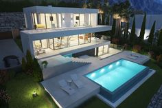 an aerial view of a modern house at night with pool and lounge chairs in the foreground