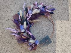 a purple and white wreath with feathers on the ground next to a tag that says, happy mother's day