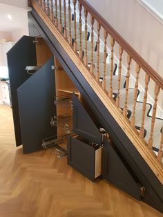 an open cabinet under the stairs in a house with wooden floors and handrails