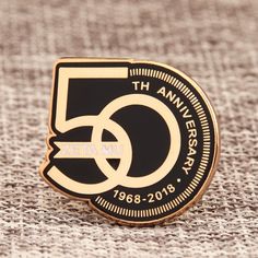 a black and gold 50th anniversary pin with the number five on it's back