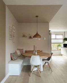 a dining room table with chairs and a bench in the corner, next to a window