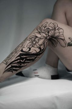 a woman's legs with tattoos and flowers on them, sitting on a bed