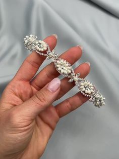 a woman's hand holding a diamond and pearled bridal bracelet in her left hand