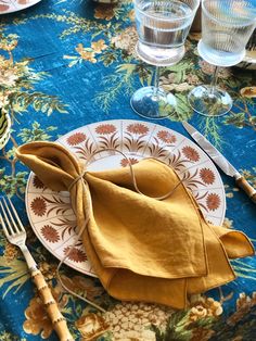 a plate with a napkin on top of it next to some glasses and silverware