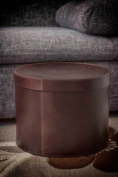 a brown leather ottoman sitting on top of a rug