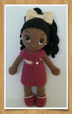 a crocheted doll with black hair wearing a red dress