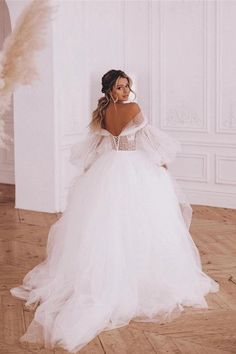 a woman in a white wedding dress standing on the floor with her back to the camera