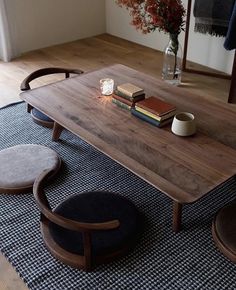 a wooden table sitting on top of a rug next to two chairs and a vase