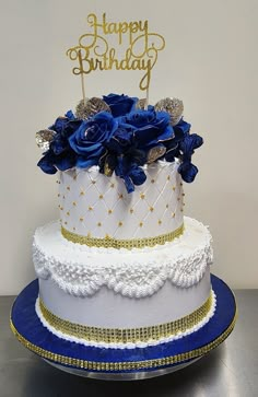 a white and blue birthday cake with gold decorations