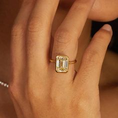 a woman's hand with a ring on it and an emerald stone in the middle