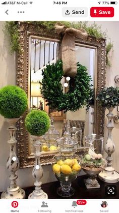 a table topped with lots of vases filled with lemons and greenery next to a mirror