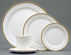 white and gold dinnerware set on grey background