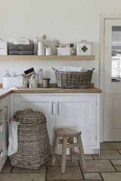 a kitchen with white cabinets and baskets on the counter top, along with two stools