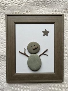 a rock snowman with a star in the middle and a wooden frame on top