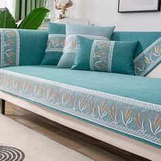 a couch with blue and gold pillows on it in front of a white carpeted floor