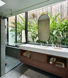 a bathroom with a sink, mirror and plants in the shower area on the side