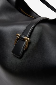 Black leather tote bag from Ferragamo. The large tote bag is made from soft semi-glossy calfskin leather in a softened silhouette, complete with a magnetic golden Gancini clasp that fastens the top strap. Tonal lining and a zipped pocket inside. Measurements: L30 x H13 x W9 cmMade in Italy Black Leather Tote Bag, Black Leather Tote, Black Tote, Large Tote Bag, Black Tote Bag, Large Tote, Leather Tote Bag, Large Black, Inside Pocket