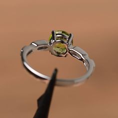 It is a natural peridot ring. The main stone is 7mm*7mm brillion cut, weight about 1.40 carats. The basic metal is sterling silver and plated with rhodium. To change the metal to a solid gold (white/rose) or platinum is also available, please ask for a quotation if you want. You can also go to my shop Home for more elegant rings: https://www.etsy.com/shop/godjewelry?ref=hdr_shop_menu Peridot is August birthstone Customization is always welcome and please feel free to contact with me if you have Silver Peridot Jewelry With Center Stone, Peridot Bezel Setting Promise Ring, Peridot Jewelry With Center Stone In Round Cut, Peridot Promise Ring With Bezel Setting, Peridot Jewelry With Round Cut Center Stone, Silver Peridot Solitaire Ring, Round Cut Peridot Jewelry With Center Stone, Peridot Jewelry With Center Stone, Peridot Ring With Prong Setting In Round Cut