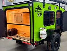 an off - road camper with the doors open and lights on is parked in a garage